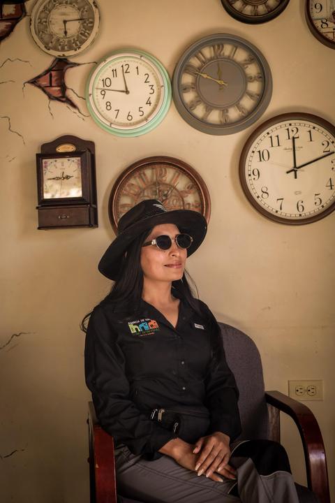 A guide beside a wall of clocks