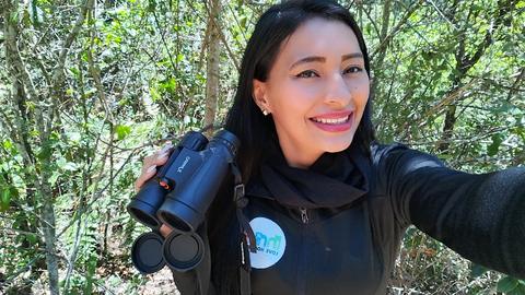 A guide with binoculars taking a selfie in the forest