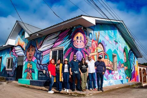 A group in front of a colourful mural