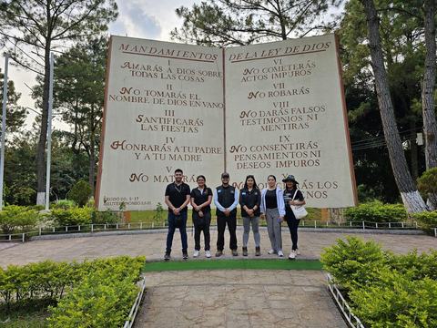 Grupo frente a un gran monumento de piedra con los Mandamientos en un parque