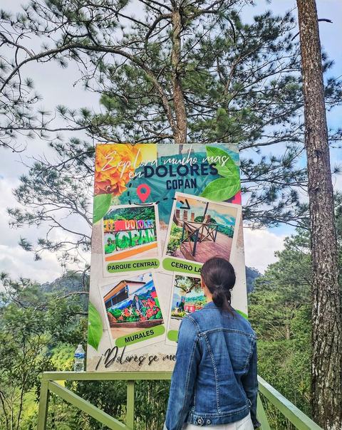 Mujer junto a un rótulo que dice «Explora mucho más en Dolores Copán»